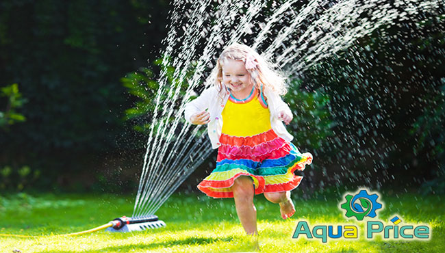 Полив газона круговым дождевателем Дождеватель круговой поливает девочку на газоне